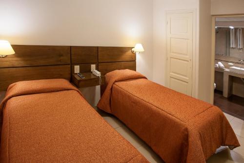a hotel room with two beds and a bathroom at Hotel Carollo in Mendoza