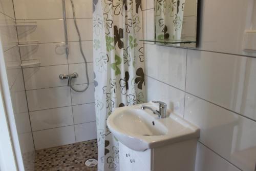 uma casa de banho com um lavatório, um espelho e um chuveiro em Nurmeveski Holiday House em Nurme