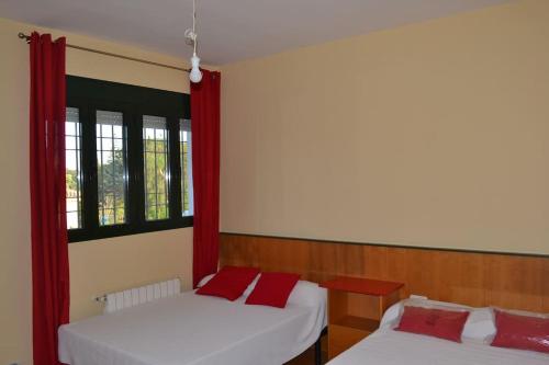 エル・プエルト・デ・サンタマリアにあるVilla las Redesの赤いカーテンが備わるドミトリールームのベッド2台分です。