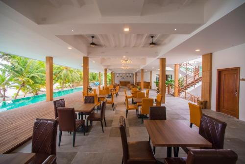a restaurant with tables and chairs and a pool at Kiha Beach in Dharavandhoo