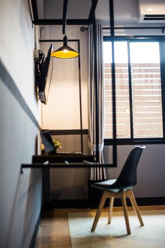 a desk and a chair in a room with a window at BY Hotel Kanchanaburi in Kanchanaburi