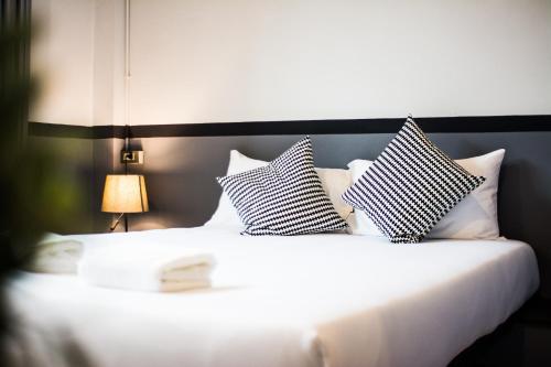 a white bed with black and white pillows on it at BY Hotel Kanchanaburi in Kanchanaburi