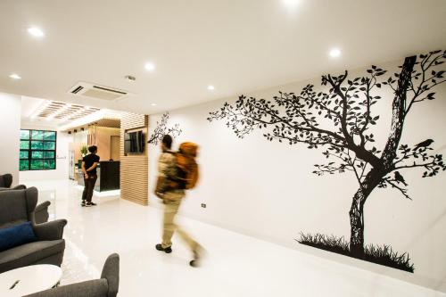 a man walking in a room with a tree on the wall at BY Hotel Kanchanaburi in Kanchanaburi