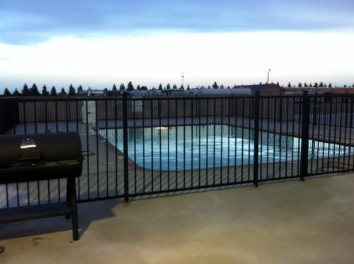 a black fence with a swimming pool behind it at Southern Inn and Suites Kermit in Kermit