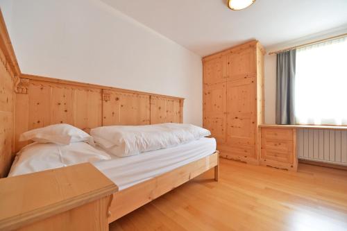 Schlafzimmer mit einem Bett mit einem Kopfteil aus Holz und einem Fenster in der Unterkunft Villa sulla passeggiata in St. Ulrich in Gröden