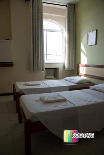 a room with three beds and a window at Hotel Porto Da Barra in Salvador