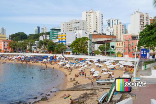 um grupo de pessoas em uma praia com guarda-sóis em Hotel Porto Da Barra em Salvador