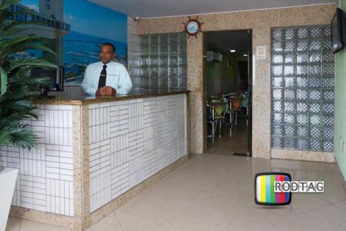 a man standing at a bar in a restaurant at Hotel Porto Da Barra in Salvador