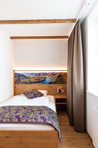 a bedroom with a bed and a painting on the wall at Weißes Rössl, Mühldorf in der Wachau in Mühldorf