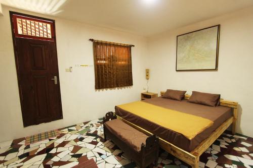 a bedroom with a bed and a window and a door at Posnya Seni Godod Art Gallery & Homestay in Yogyakarta