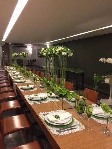 a long table with plates and vases filled with flowers at Mara Turismo Hotel in Catalão