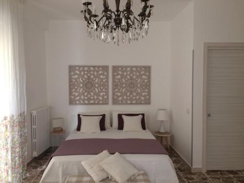 sypialnia z dużym łóżkiem i żyrandolem w obiekcie appartamento al primo piano in centro storico con terrazzo panoramico w mieście Caltagirone