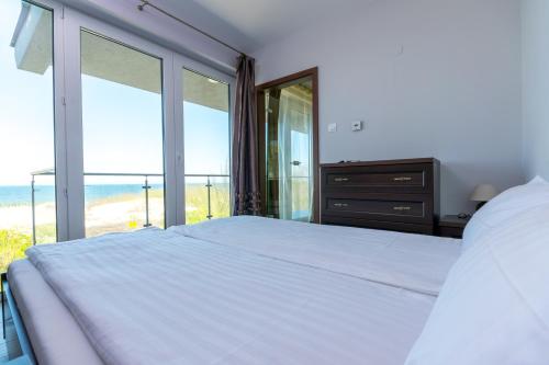 a bedroom with a bed with a view of the beach at Apartamenty Amon z widokiem na morze in Darlowko