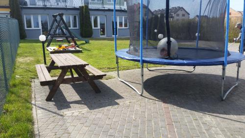 a swing set with a wooden table and a picnic table at Azalia 32 Mielno l in Mielno