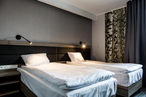 Hotel Mazurek في Koło: سريرين في غرفة الفندق ذات شراشف بيضاء