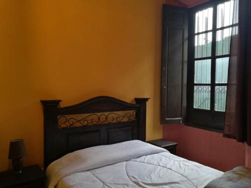 a bedroom with a bed and two windows at Hotel Casa Quetzaltenango in Quetzaltenango