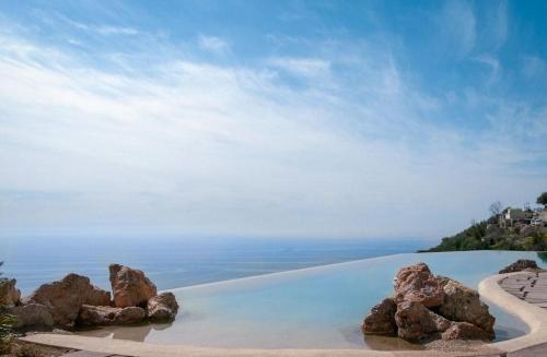 a pool of water with rocks on a beach at Monastero Santa Rosa Hotel & Spa in Conca dei Marini