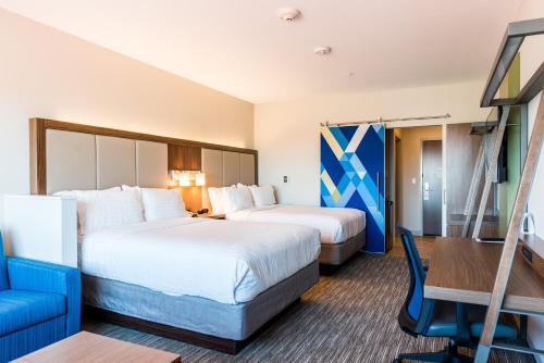 a hotel room with two beds and a blue chair at Holiday Inn Express & Suites Madison, an IHG Hotel in Madison