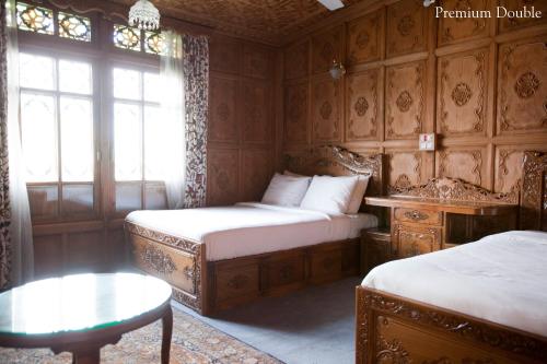 a bedroom with two beds and a table and a window at Mascot Houseboats in Srinagar
