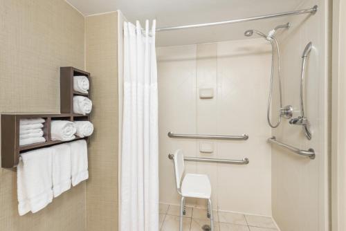 a bathroom with a shower and a white chair at Wingate by Wyndham Springfield in Springfield