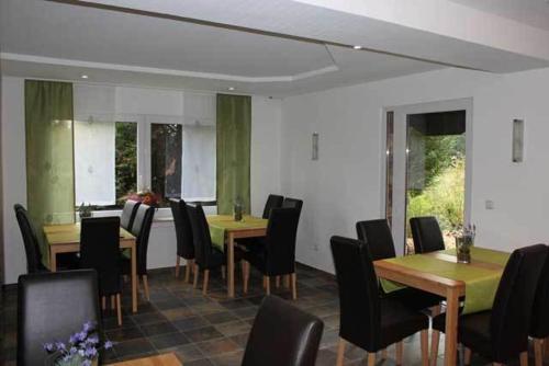 a dining room with wooden tables and black chairs at Hotel Tau-Lünne in Haselünne