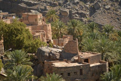 an old building on a mountain with palm trees at Misfah Old House in Misfāh