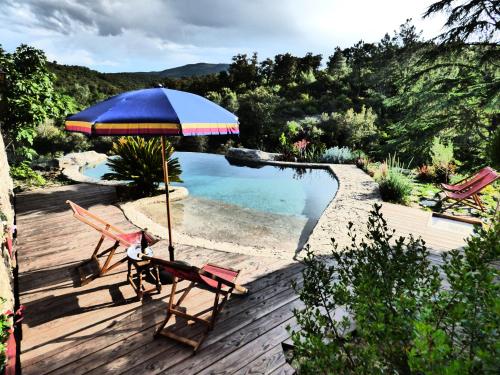 Caixas的住宿－Mas de la Fariole，一个带两把椅子和一把遮阳伞的庭院,毗邻一个游泳池