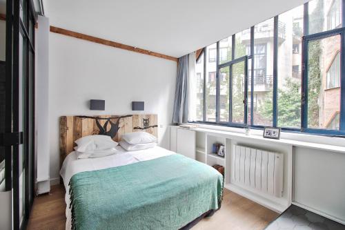 a bedroom with a bed and large windows at Sloth Loft Montmartre in Paris