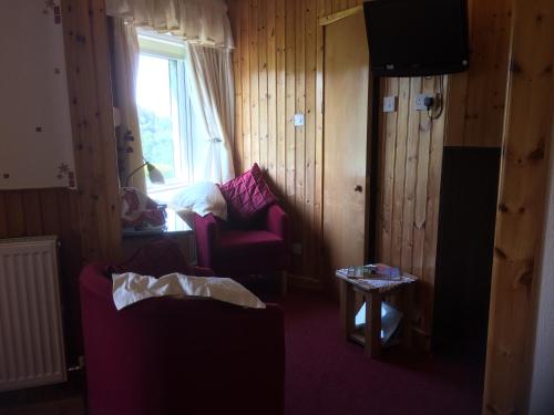 a living room with a red couch and a window at Rhiwiau Guesthouse in Llanfairfechan