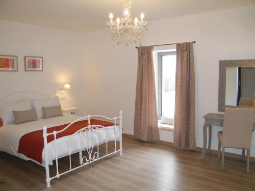 a bedroom with a bed and a table and a chandelier at Clos Vieux Rochers Vineyard in Puisseguin