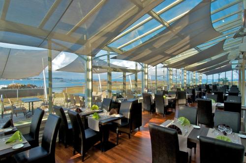 a restaurant with tables and chairs with a view of the ocean at Best Western Plus Les Terrasses de Bréhat in Ploubazlanec