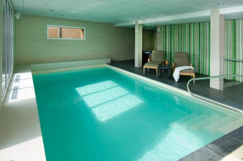 una piscina con agua azul en una habitación en Best Western Plus Les Terrasses de Bréhat, en Ploubazlanec