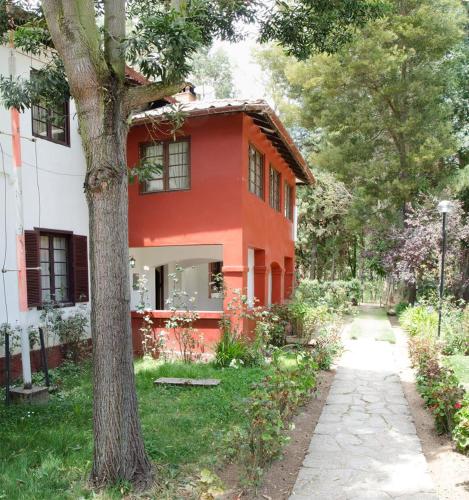 a red house with a tree next to a sidewalk at Centro Vacacional Huaychulo in Concepción