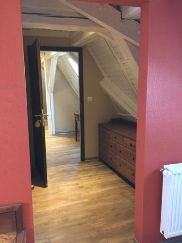 an attic room with a staircase and a wooden dresser at Auberge Le Meisenberg in Châtenois