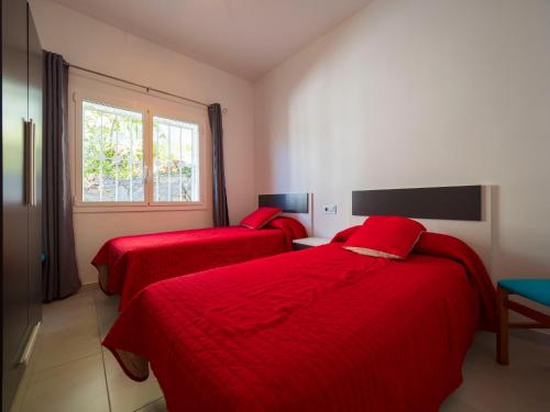 two beds in a room with red sheets and a window at InmoSantos Casa Tordera in Roses