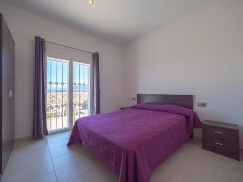 a bedroom with a purple bed and a large window at InmoSantos Casa Tordera in Roses