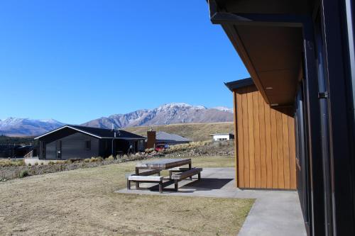 two benches sitting outside of a building with mountains in the background at Loudon Lodge - Lake Tekapo in Lake Tekapo