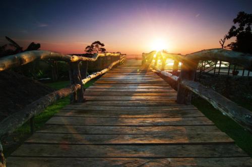 a wooden pathway with the sunset in the background at The Duyan House at Sinagtala Resort in Orani