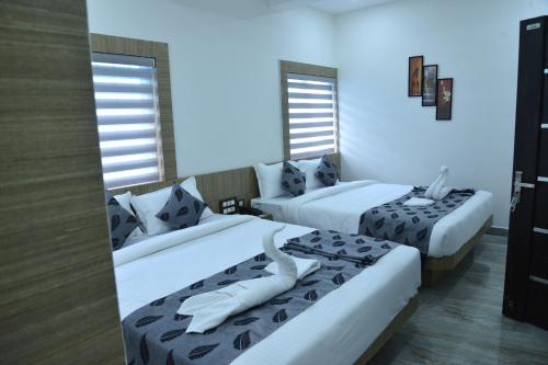 a hotel room with two beds and two windows at Suroor Tourist Home in Virajpet