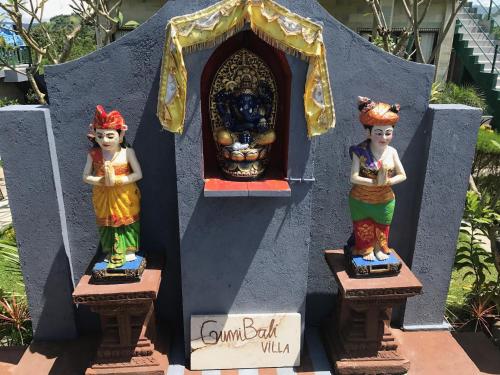a group of three statues in front of a shrine at GumiBali Villa in Tirtagangga