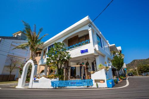a white building with blue balconies on a street at 墾丁愛情海民宿 in Kenting