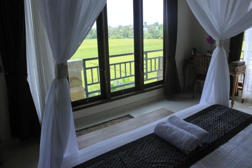 a bedroom with a bed and a large window at Heaven Villa Ubud in Ubud