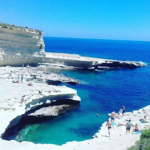 a group of people on a beach near the ocean at St. Peter's Pool Holiday Apartment in Marsaxlokk