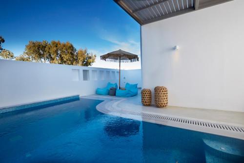 a swimming pool with blue water and an umbrella at Eolia Kamari Villa in Kamari