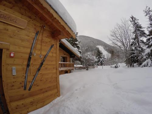 a log cabin with snow on the ground next to it at Chalet Alpina Hotel & Apartments in La Thuile