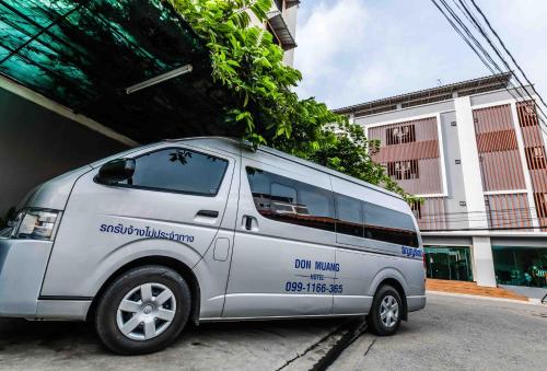 una furgoneta plateada estacionada al lado de una calle en Don Muang Hotel en Bangkok