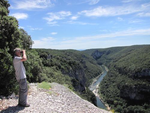 a man standing on top of a mountain taking a picture of a river at Cairenou Location in Saint-Martin-dʼArdèche