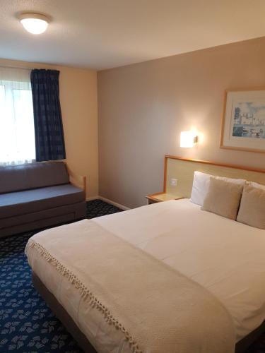 een hotelkamer met een groot bed en een bank bij Travel Plaza Hotel in Desborough