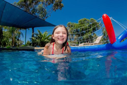 a girl in the water in a swimming pool at Shepparton Holiday Park and Village in Shepparton