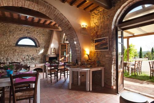 un restaurante con mesas y sillas y una pared de piedra en Agriturismo Podere Campaini, en Volterra